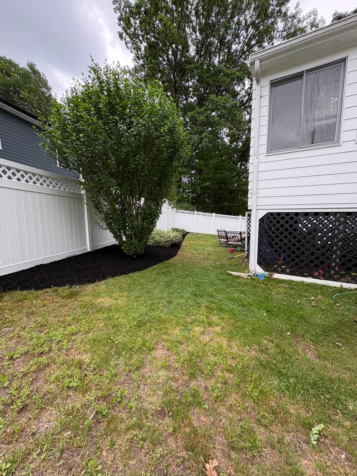 Cleaned-up backyard with fresh mulch beds along a white fence